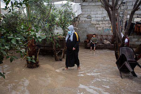 A Palestinian woman walks through her house after it was flooded by rain in Khan Yunis, in the southern Gaza Strip.