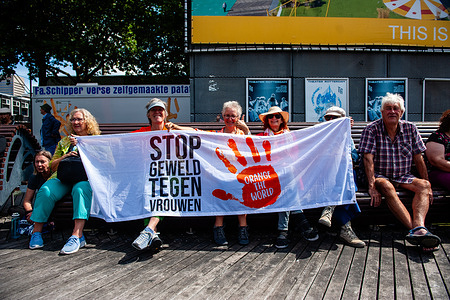 A group of protesters sit on a bench while holding a banner during a demonstration against femicide in Rotterdam. The Dutch feminist organization "Dolle Mina" held a national protest march against femicide in Rotterdam. This is in response to two murders of women in less than a week. In both cases, the suspect turned out to be a (former) partner of the victim. "Dolle Mina" demands that femicide must be recognized as a "specific and structural form of gender-based violence." During the speech of one of the parents of one of the victims, a man ran onto the stage and tried to disrupt the event.