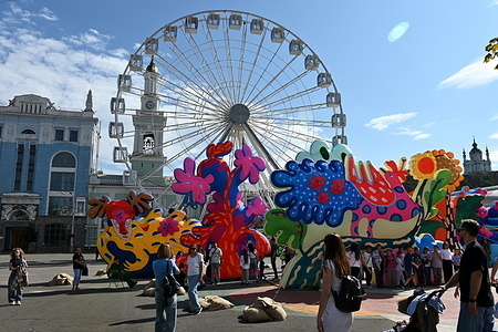Kyiv residents and guests of the capital walk along Kontraktova Square against the background of the Ferris wheel and installation of inflatable sculptures by the New York art duo 'Chiaozza' (Adam Frezza and Terri Chiaode) inspired by the work of Ukrainian artist Maria Prymachenko, amid the Russian invasion of Ukraine. Ukraine continues to defend itself against Russian military aggression for the 4th year after the invasion on February 24, 2022, with shelling of the territory of Ukraine continuing daily.