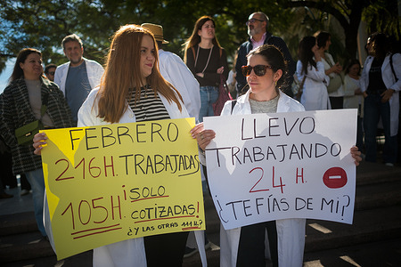 Two protesters are seen holding placards denouncing their professional situation as they take part in a demonstration during the general doctors' strike. Doctors across Spain stage a strike which will last at least one week, against the Framework Health Statute and In favour of improved working conditions, including a reduction in their workload.