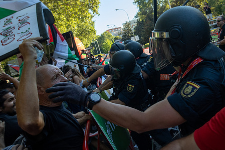 A riot police officer covers a protester's mouth. during the demonstrations in Madrid, while the 21st stage of the Vuelta a España was canceled. The Vuelta a España was marked by protests in support of the Palestinian people.