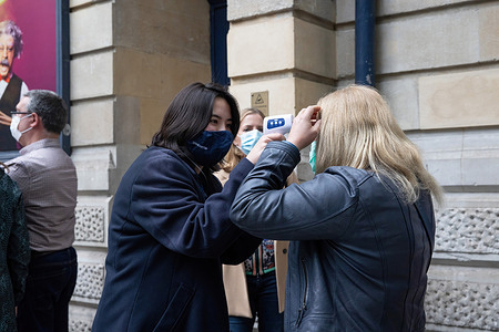 A member of the theatre staff checking body temperatures of the audience before letting them into the theatre. Despite failure on lifting lockdown requirements on Monday, theatres are still able to open to their audiences if they adhere the recommended social distancing and infection control measures set by the UK government.