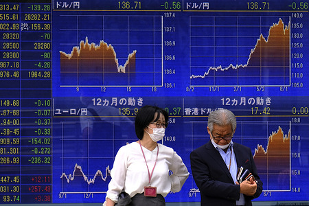 People stand in front of a stock prices board in Tokyo. The Tokyo stock market reopened for 2023 with prices on a decline, snubbing the old Japanese market aphorism that stock prices "jump" in the Year of the Rabbit.