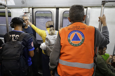 A civil protection worker patrols a subway car at the Poder Judicial station following a bomb threat at the capital's Court of Justice. A bomb threat was reported at the Mexico City Courthouse, prompting the evacuation of the building for everyone's safety. The threat triggered alarm among employees and visitors who were conducting business and attending hearings. Uncertainty gripped the building as specialized personnel began inspections to rule out any potential risks.