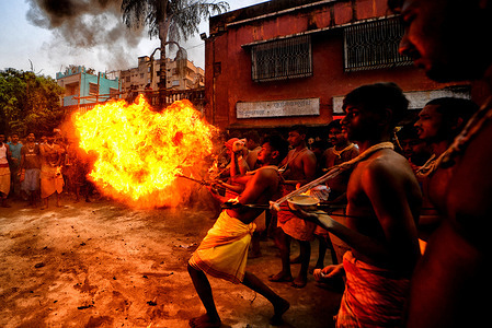 Hindu devotees seen playing with fire in front of a Shiva Temple during Charak Puja Celebration. Charak Festival is one of the oldest Folk festivals as devotees show their faith by self inflicting pain in the belief that Lord Shiva will help them overcome troubles in their daily lives.