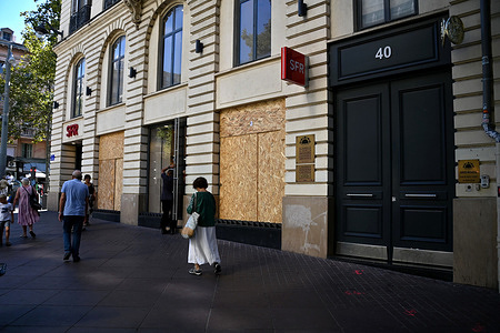People walk past an SFR mobile phone shop whose windows have been boarded up, on the corner of La Canebiere and Rue Pavillon in Marseille. Fearing overflows and acts of vandalism, businesses in downtown Marseille have barricaded themselves for the day of demonstrations on September 10, 2025, resulting from the movement of the collective "Bloquons tout" (Let's Block Everything), calling on the French to mobilize to paralyze the country with a series of protest actions and civil disobedience in response to the austerity policies of the French government.
