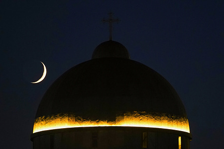 A view of the crescent moon rising behind the dome of the Catholic Assyrian of the East Virgin Mary Church in Dohuk in the Kurdistan Region of Iraq.