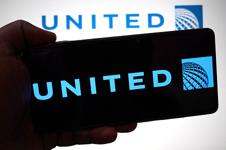 In this photo illustration, the United Airlines logo is seen displayed on a smartphone and in the background.