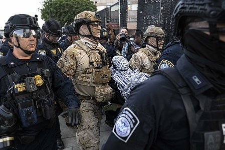 DHS officers carry a protester that was chased down and arrested. Protesters clash with DHS officers at the Metropolitan Detention Center (MDC) in Los Angeles, during the nationwide "Mayday" protests occurring across the United States.