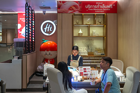 A woman is having her fingernails prettified by a nail technician at Haidilao, the best-known Chinese chain hotpot restaurant in the Central World shopping mall.