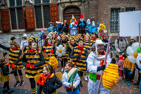 People dressed like bees are performing next to the Mayor of Nijmegen (Smurfette). The Carnival was celebrated with a parade featuring a colorful collection of themed floats, carnival groups, and associations. The main attraction each year is the costume that the Mayor of the city, Huber Bruls, will be wearing. This year, the theme was the Smurfs.