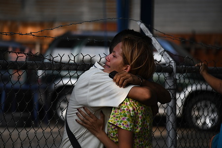 Relatives of detainees seen comforting each other by hugging.
Relatives of detainees in the police headquarters of Carabobo, in the city of Valencia in Carabobo state, remain outside the police station waiting to find out if their detained relatives is still alive. A fire inside the cells of the police station taken the lives of 66 detainees and 2 women who were visiting. Family members alleged that the police burned them alive inside the cells after a fight with them. Relatives also reported that police sells weapons inside the prison and charge money for visiting. For more than 20 hours the national government has not release statements and the list of victims.
