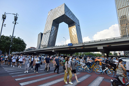 Pedestrians wearing face masks walk across a zebra crossing at the Guomao CBD business district in Beijing.