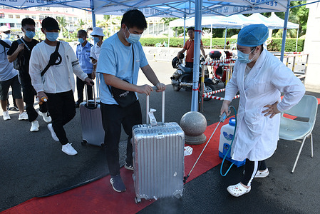 University health workers seen sanitizing student luggages who return to school. 
Students are required to check their health codes, travel records and student ID cards before they enter at school only after their body temperature is normal.