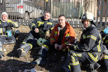 Firefighters rest on the ground after rescuing a fire alarm at the building in Kyiv following the Russian shelling attack. A building in Kyiv was destroyed following the shelling attack of the Russian military troops. Russia invaded Ukraine on 24 February 2022, triggering the most extensive military attack in Europe since World War II.