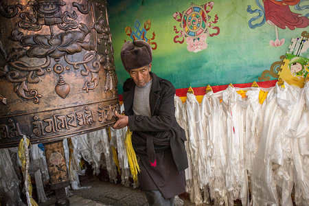 An old man seen turning a large prayer wheel at the Tibetan Buddhist Ganden Sumtseling Monastery in Shangri-La.