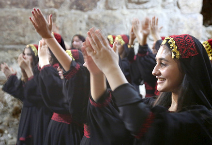 Palestinian girls perform the Palestinian Dabke dance while wearing traditional silk-embroidered costumes on an iron bridge at the archaeological site in the town of Sebastia (west of Nablus in the West Bank) during a festival celebrating traditional Palestinian attire and the Dabke dance.
