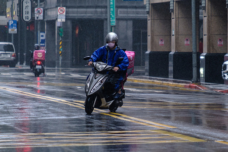 A man rides a scooter on a rainy day.