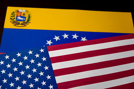 In this photo illustration, the American flag and the Venezuelan flag are seen displayed on the table.