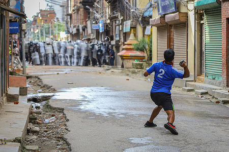A devotee throwing stones towards police forces during clashes.
Nepalese devotees and riot police clash ahead of the Rato Machindranath chariot festival procession that has been deferred this year due to the coronavirus pandemic. The Machhindranath Jatra or the Bunga Dyaḥ Jatra was due to take place in April.