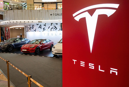 A showroom displays the American automaker company, Tesla Motors, electric (EV) vehicles and a company logo sign at a retail shopping mall in Hong Kong.