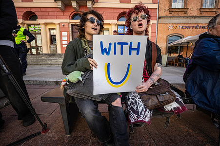 Young activists hold a placard showing solidarity with Ukraine. Ukrainians in Poland celebrated the 35th anniversary of Ukraine's independence with a special event in Warsaw's Castle Square. Varsovians and Ukrainian immigrants came together to support Ukraine, thanking the soldiers fighting for its freedom, and others who "stand with Ukraine" in other ways. The event featured an awards ceremony, speeches, and musical performances by Polish star Krzysztof Zalewski and Ukrainian folk band Dakhabrakha. Polish right-wing nationalists staged a counter demonstration against Ukrainian migration and the Ukrainian massacre of Poles at Wolyn during World War II. A group of young Antifa activists gathered to protect the Ukrainian celebration.