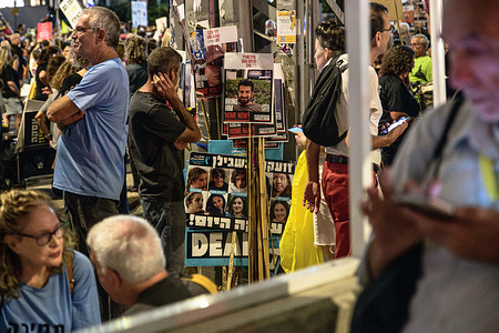 An Israeli protestor looks at placards with the photos of the Israeli hostage at the end of the demonstration. Supporters demonstrated with family members of the Israeli hostages against Prime Minister Benjamin Netanyahu, demanding an immediate hostage deal and ceasefire in front of the IDF headquarters.