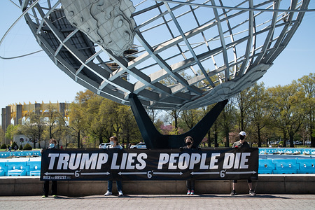 The Rise and Resist organisation activists hold a banner protesting against the President of the United States's decisions regarding the Coronavirus pandemic at the Unisphere in Corona Park.