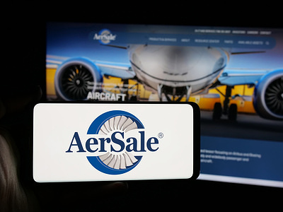 In this photo illustration, a person is holding a smartphone with the logo of US aviation aftermarket company AerSale Inc. on screen in front of website.