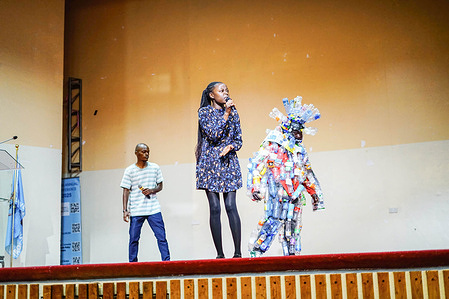 Performers sing alongside an artist wearing an outfit made from plastic waste during the annual Academic Council of the United Nations System (ACUNS) conference at the University of Nairobi, held under the theme of environmental multilateralism and human development.