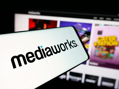 In this photo illustration, a smartphone with the logo of media company MediaWorks New Zealand is seen displayed on screen in front of website.