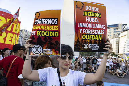A protester raises placards expressing her opinion during the demonstration. The protest held outside the Obelisk against what demonstrators described as government inaction in tackling wildfires took place simultaneously with rallies in major Patagonian cities. The fires have already burned more than 25,000 hectares in the provinces of Chubut, Río Negro and Neuquén.