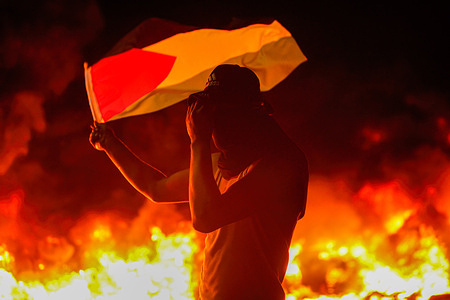 Palestinian demonstrator holds a flag during the confrontation with Israeli forces, near the city of Nablus in the northern West Bank.Palestinians held a protest against the punitive measures taken by the Israeli Prison Service against Palestinian prisoners in Israel, after six prisoners escaped from Gilboa Israeli prison.