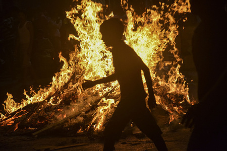 A boy is seen performing rituals by surrounding the burning effigy during the festival.
Holika Dahan festival takes place just before the day of Holi. People make effigies out of leaves, dry wings, fallen branches of tree and wastes and then burn it as the symbol of evil. People gather around it and dance to celebrate this moment.