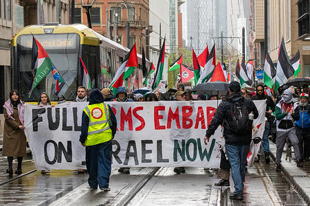 Protesters with a banner block a Tram during the demonstration. Despite heavy rain a crowd of approximately 500 protesters gathered in Manchester's St Peter's Square to support Palestine and call for an arms Embargo on Israel. The protesters marched through the city centre blocking trams and disrupting traffic.