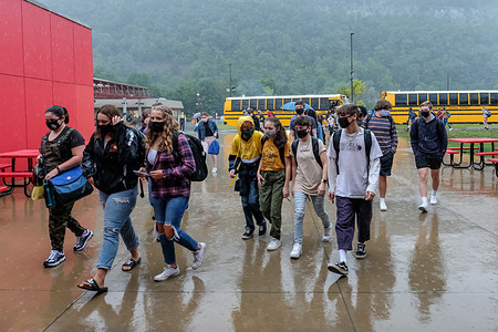 Students wearing face masks as a preventive measure arrive at Delaware Valley High School during the first day of school on a rainy morning.