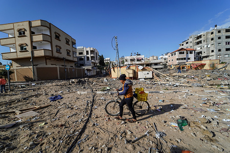 A child pushing his bicycle walks through rubble after an Israeli airstrike in Gaza.
Israeli air strikes hit several places across Gaza over the night which were in response to a rare long-distance rocket attack from the Palestinian enclave that hit a home in Tel Aviv and injured 7 person on Monday.