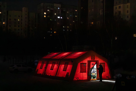 A mobile tent ‘Point of Invincibility’ is seen illuminated against the backdrop of a dark residential area during a power outage. Residents gather inside the shelter to warm up, drink hot tea, and charge their mobile phones. A massive attack involving 34 missiles and 339 drones caused widespread energy system failures, leaving more than one million residents without power or heating as temperatures dropped to minus 20°C. Damage to critical infrastructure affected around 4,000 residential buildings and government offices, forcing an estimated 600,000 people to flee the capital and prompting UN condemnation over possible violations of the laws of war