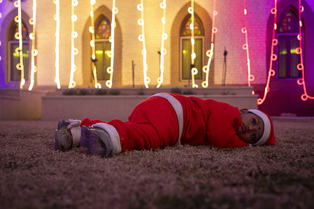 A child dressed in a Santa Claus costume rests outside Holy Family Catholic Church decorated with lights on Christmas Eve in Srinagar, Indian administered Kashmir. Christmas is celebrated across the world on December 25 to commemorate the birth of Jesus, the central figure of Christianity.