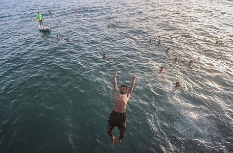 A Palestinian boy jumps to swim from the edge of the Gaza port into the Mediterranean Sea in Gaza City. Palestinian boys jump to swim from the edge of the Gaza port into the Mediterranean Sea on a hot day as temperatures rose to 40 degrees Celsius.