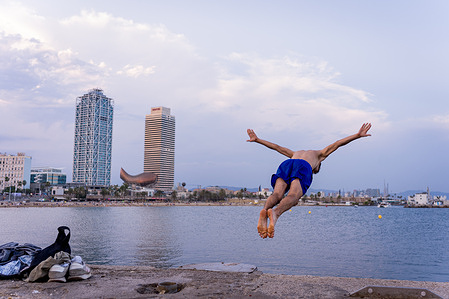 Boys jump from the pier in the Barceloneta beach at sunset. With temperatures reaching over 46 degrees celsius in parts of the country, this was the hottest month of June ever recorded in Spain, due in part to the effects of climate change. Several deaths were recorded across the country and Europe.