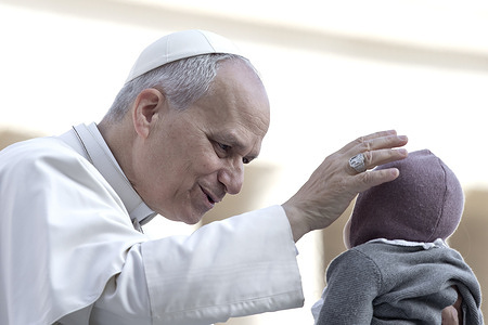 Pope Leo XIV greets a child as he arrives for his weekly general audience in St. Peter's square at the Vatican.