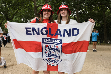 Two football fans in support of The Lioness pose for a portrait. England's women football team, also know as "The Lioness", has successfully defended the Euros title, defeating Spain 3-1 on penalties. A victory parade and ceremony take place at the Queen Victoria Memorial in front of Buckingham Palace, where the team is greeted by masses of fans.