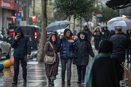 People walk with umbrellas past shops on Bahariye Street. Heavy rain in Istanbul negatively affected life in Kadikoy. People were seen walking with umbrellas to protect themselves from the rain.