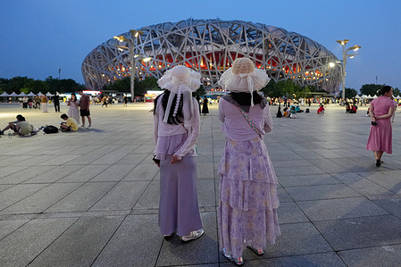 Tourists stand on Landscape Avenue to watch the Bird's Nest, as Beijing is experiencing high temperatures.