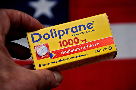 In this photo illustration, a hand holds a box of Doliprane tablets in front of the flag of the United States of America. The French pharmaceutical group Sanofi has announced that it is entering into negotiations with the American investment fund CD&R for the acquisition of the Opella branch, which markets Doliprane in particular.