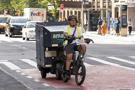 An Amazon delivery worker rides a battery-powered e-cargo bike with a towed cargo trailer in Manhattan on June 11, 2026 in New York City.