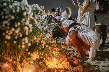 A believer lights a candle as an offering during the Festival of Iemanjá. Every year, on December 31st and February 2nd, crowds gather along Brazilian beaches, notably in Salvador and Rio de Janeiro, to present offerings to Iemanjá, the goddess of the sea, a deity celebrated in Afro-Brazilian cults such as Candomblé and Umbanda. She is the mother of the Orixás, the deities of nature. Most participants wear white as a sign of purity and peace.