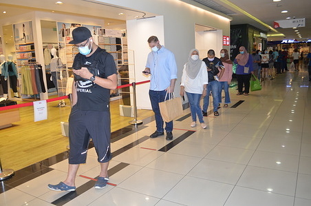 People stand in a queue to buy essential goods after the Malaysia Government announced two weeks nationwide lockdown as covid-19 cases increase.