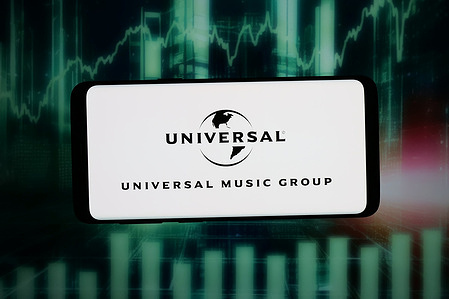 In this photo illustration, the logo of company Universal Music Group N.V. (UMG) is seen displayed on a smartphone in front of an abstract background on a computer screen.
